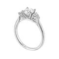 Three stone ring features a trinity of diamonds on either side, focusing the round solitaire at center, is a symbol of everlasting love.